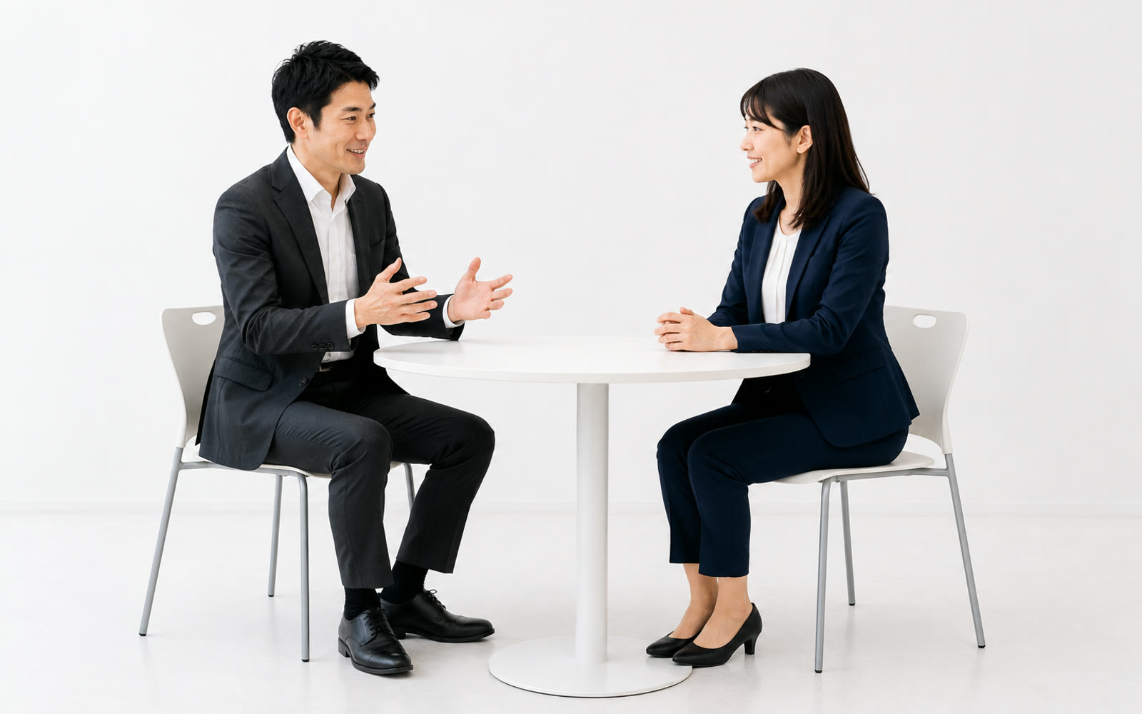 丸いテーブルで向かい合って話す2人の社員